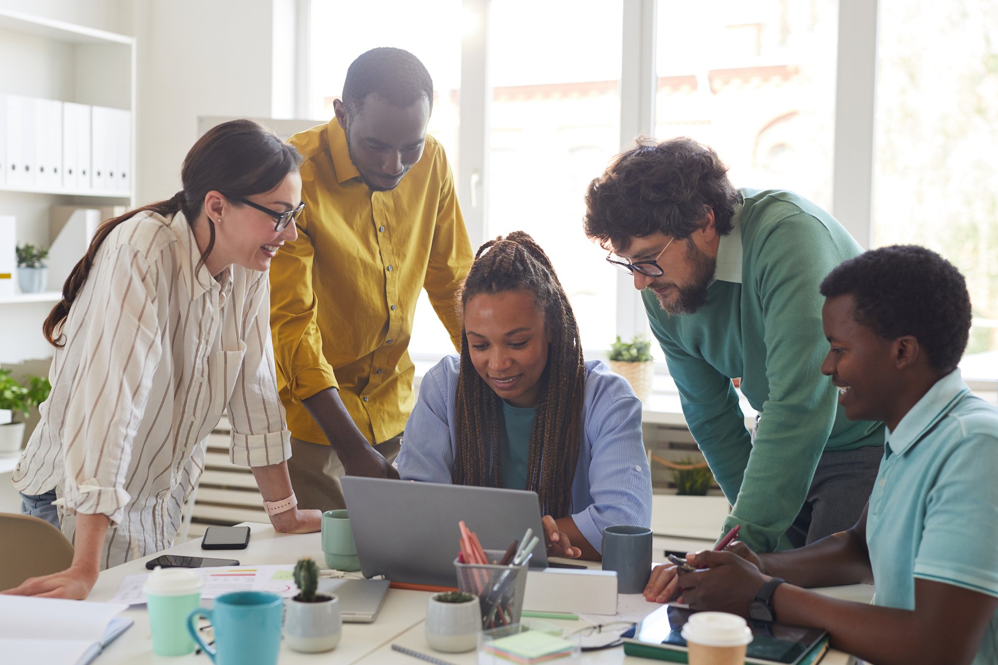 a small business owner and people working with consultant to implement business strategy on a laptop in an office